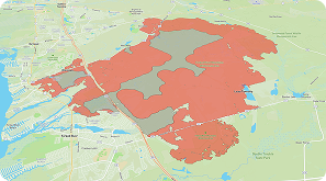 A map showing a large area shaded in red and gray, indicating different regions within a mostly green and beige landscape, with roads and waterways visible nearby.