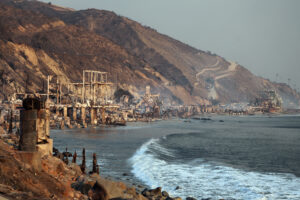 Coastal homes reduced to rubble on a scorched hillside overlooking the ocean.