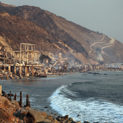 Coastal homes reduced to rubble on a scorched hillside overlooking the ocean.